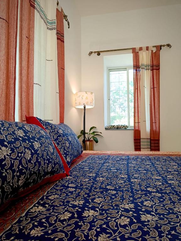 a bedroom with a bed and a window with curtains at Dheer- BnB at an Artist's Abode in Shānti Niketan