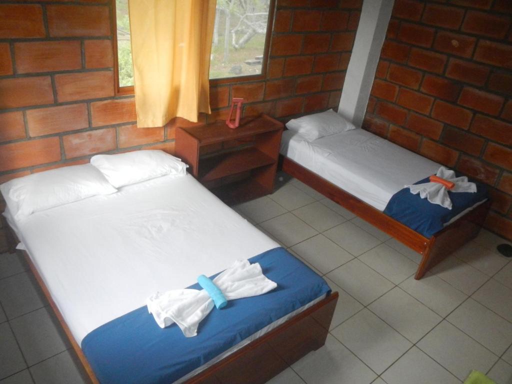 two beds in a room with a brick wall at Black Beach House in Floreana