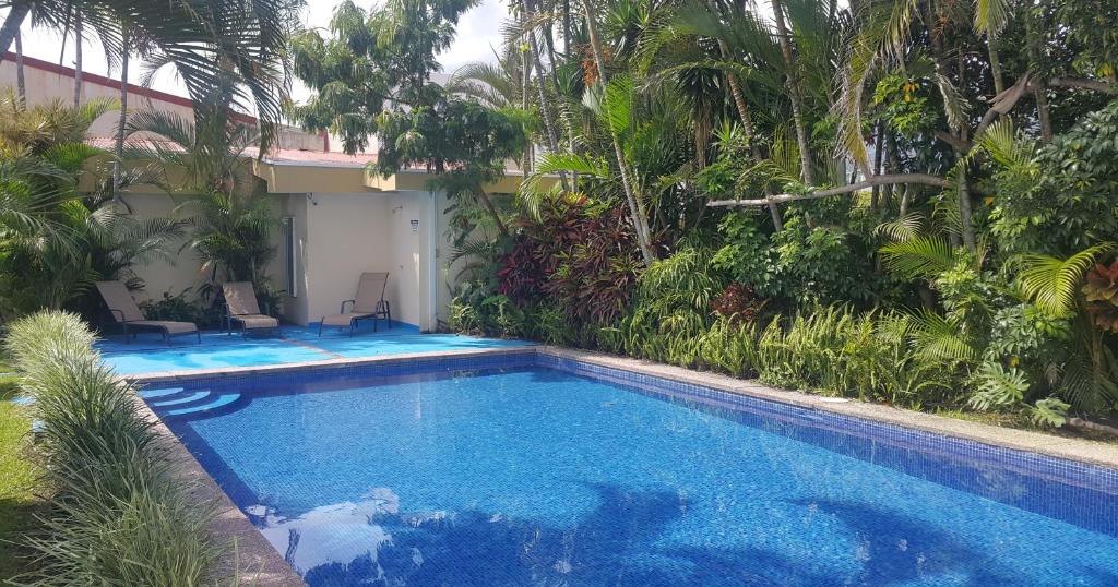 una piscina frente a una casa con árboles en Hotel Portal Colonial, en San José