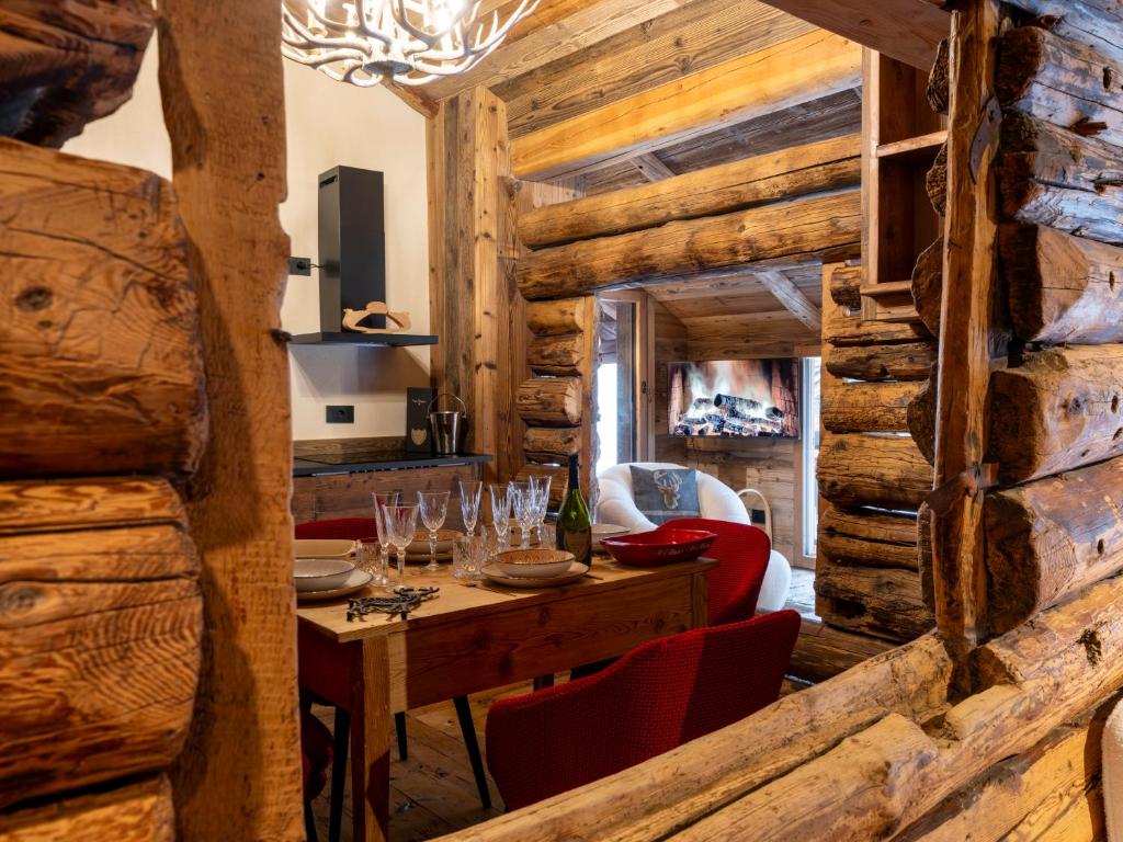 a dining room with wooden walls and a table with wine glasses at Alpine Majestic Rascard - Unique Mountain Experience with Balcony and panoramic views in Champoluc