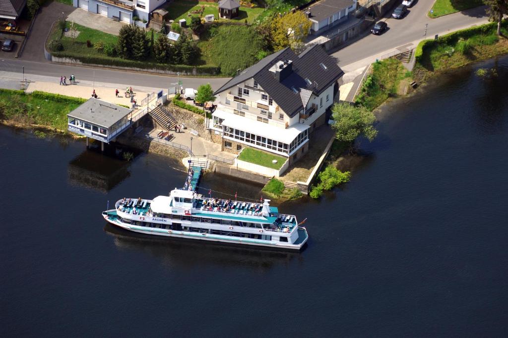 a boat floating in a river next to a house at Garni Hotel Henn in Simmerath