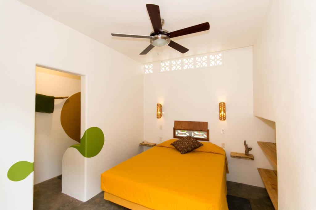 1 dormitorio con cama amarilla y ventilador de techo en Red Pepper Popoyo en Popoyo