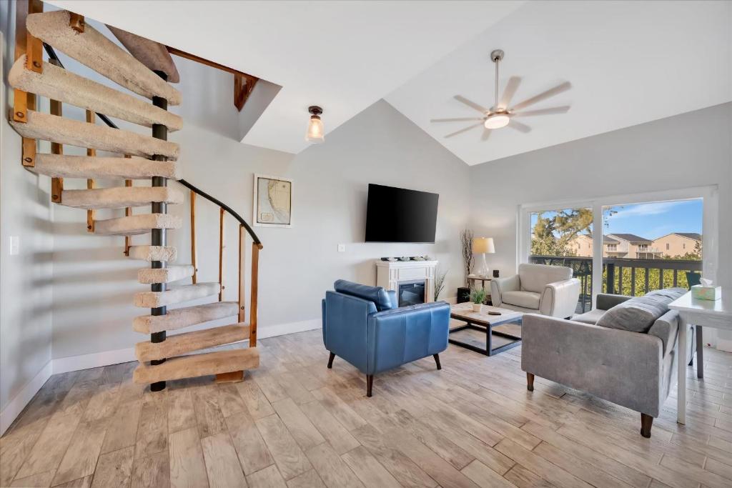 a living room with a spiral staircase and a couch and a tv at Beach Access & Heated Pool Resort Condo for 8 in Clearwater Beach