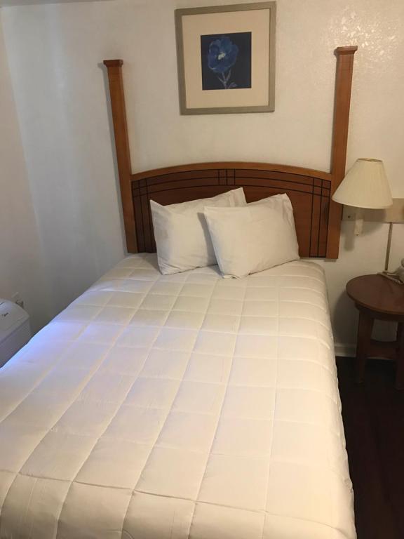 a large white bed with a wooden headboard and white pillows at Extended Stay Studios in Montgomery