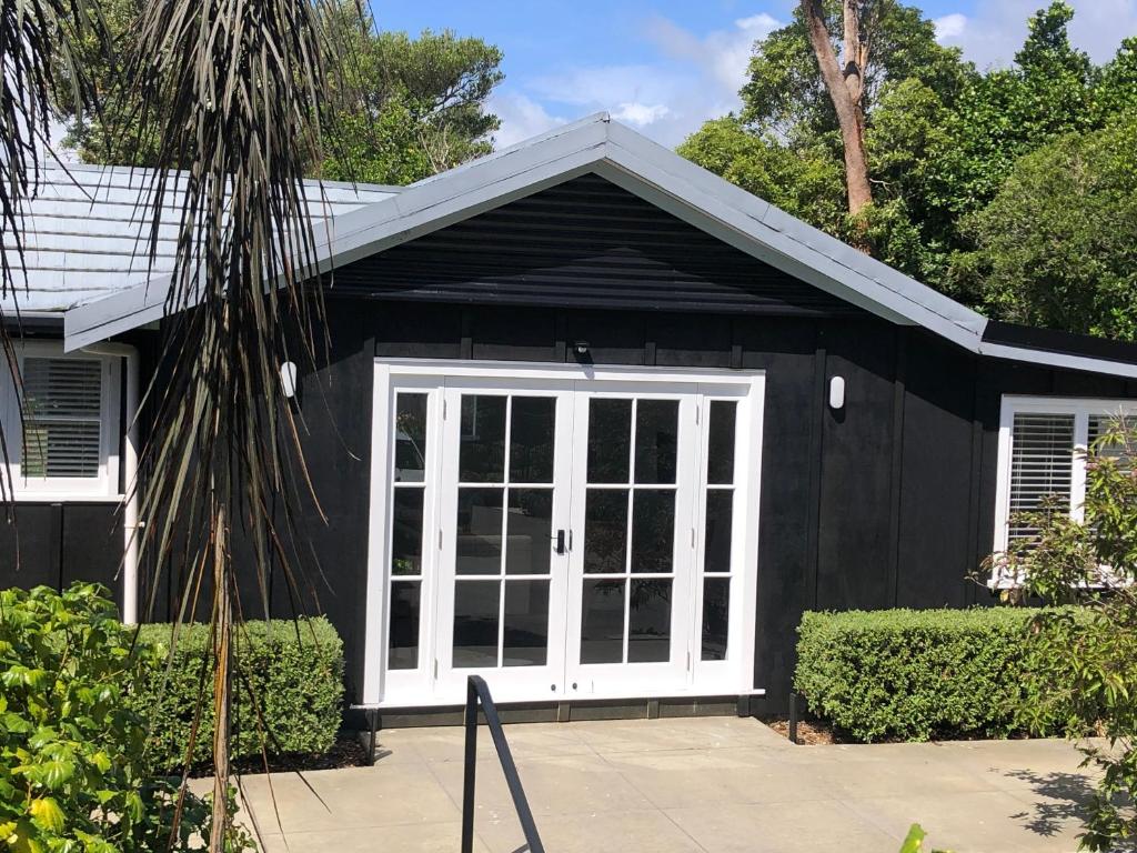 a black and white garage with a white door at Waihinau Cottage - One or Two Room Options! in Otaki