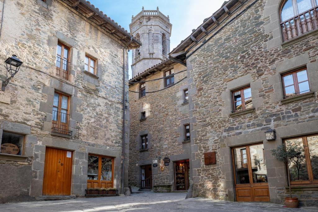 an old stone building with a tower in the background at Apartaments Can Lo in Rupit