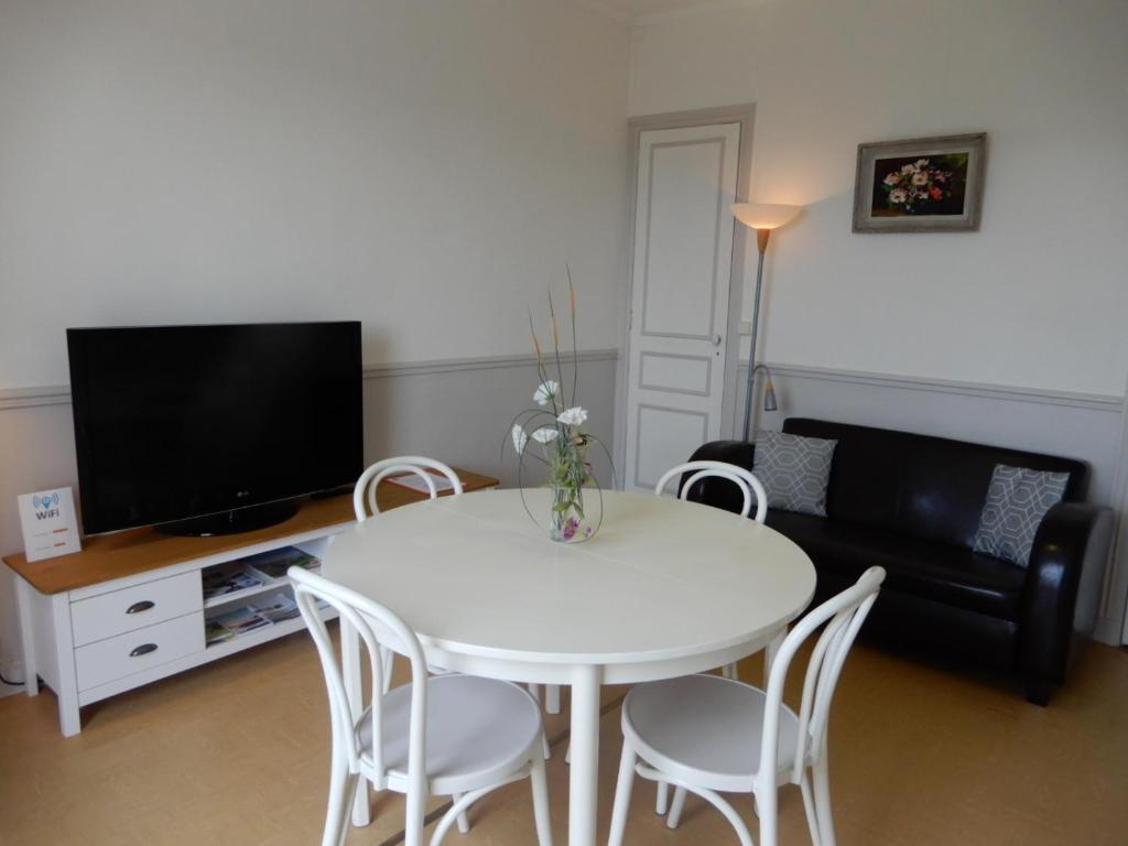 a living room with a white table and a tv at CAPRICES DE MER Appartement 1 A 2 PERS AVEC GRAND BALCON ET VUE PANORAMIQUE 300 M PLAGE LIT QUEEN SIZE PETIT DEJEUNER EN OPTION in Mers-les-Bains