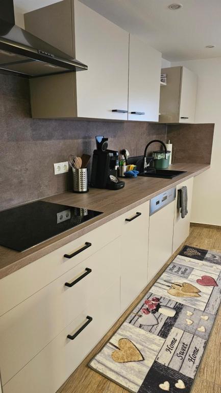 a kitchen with white cabinets and a sink and a rug at Moni's Ferienwohnung in Hammelburg