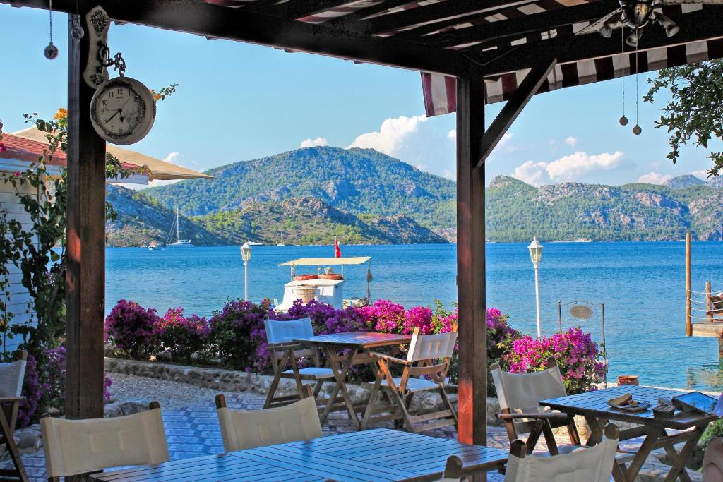 eine Terrasse mit Tischen und Stühlen und Blick auf das Wasser in der Unterkunft Losta Sahil Evi - Adults Only +12 in Selimiye