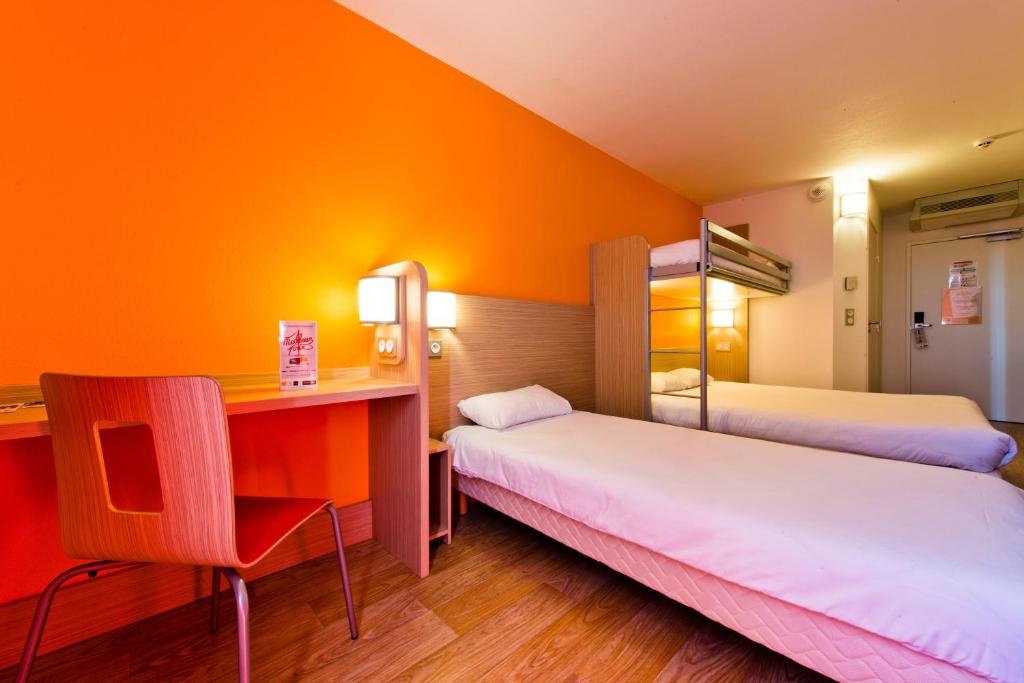 a hotel room with two beds and a desk at Premiere Classe Sens Nord- Saint Clément in Sens