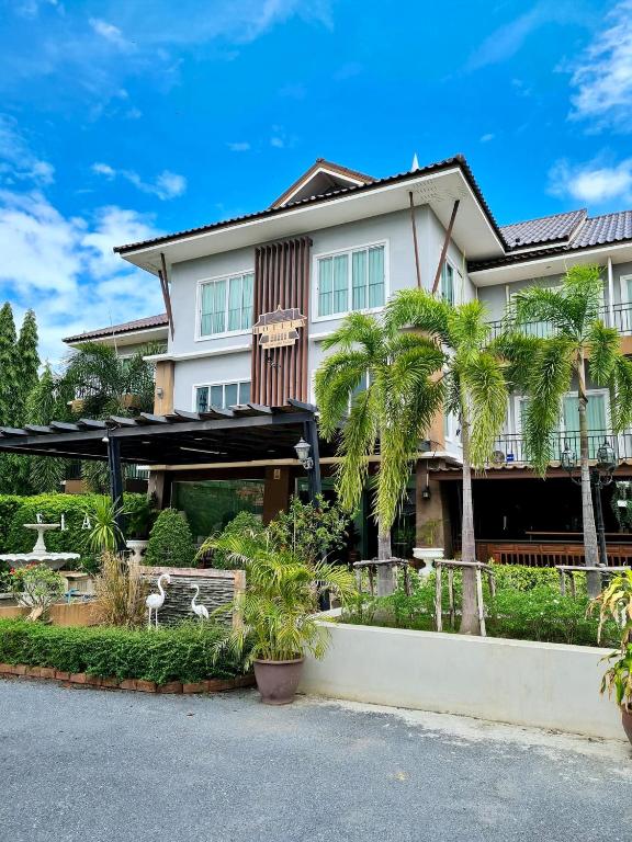 a house with palm trees in front of it at Hotela Boutique Resort in Suphan Buri
