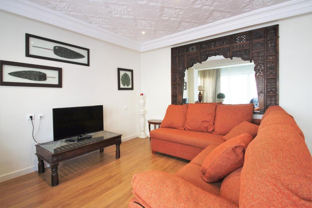 sala de estar con sofá naranja y TV en CasaTuris Pintor Lorenzo A105, en Alicante