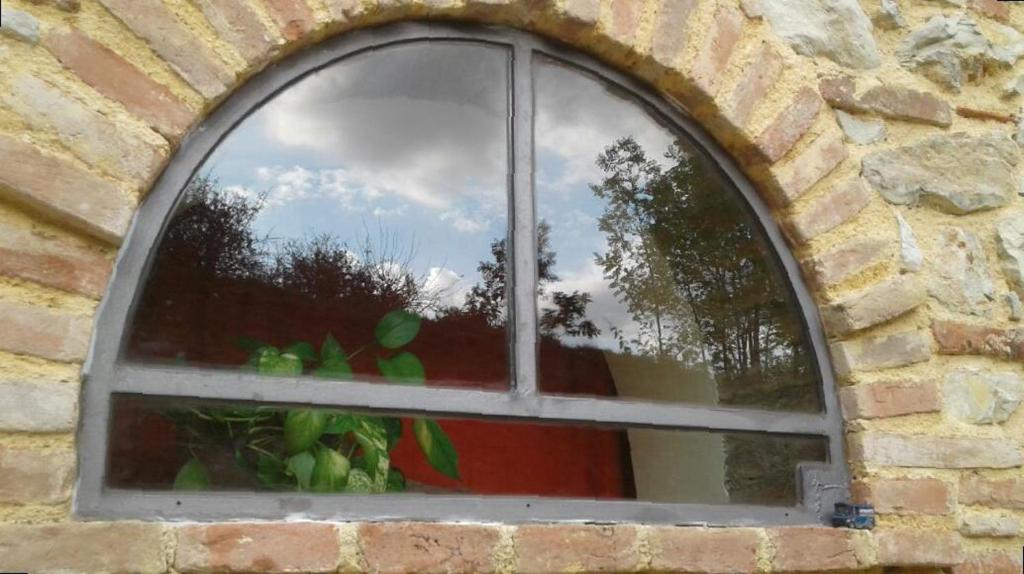 uma janela num edifício de tijolos com um reflexo de árvores em Il giardino segreto em Contigliano