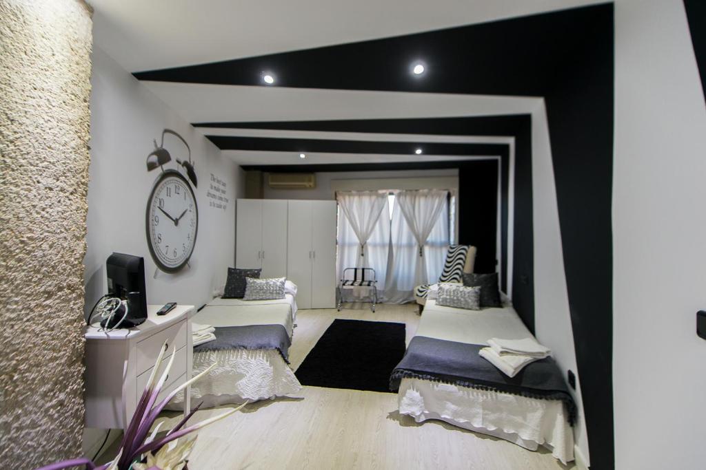 a room with two beds and a clock on the wall at Apartamentos Los Angeles in Alcañiz