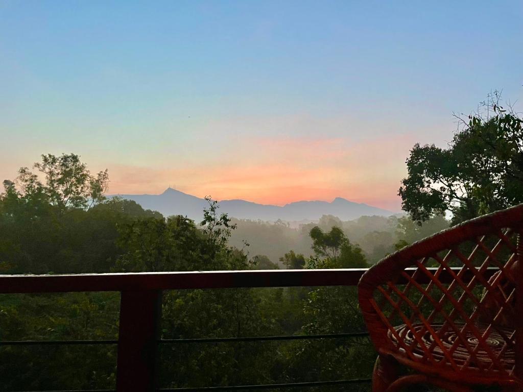 a chair on a balcony with a view of the mountains at Heaven's Acres Lodge - Private one Bedroom Cabana in Matale