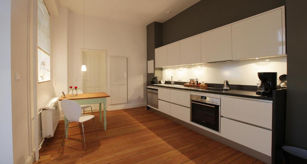 a kitchen with white cabinets and a wooden floor at quartier kiel in Kiel