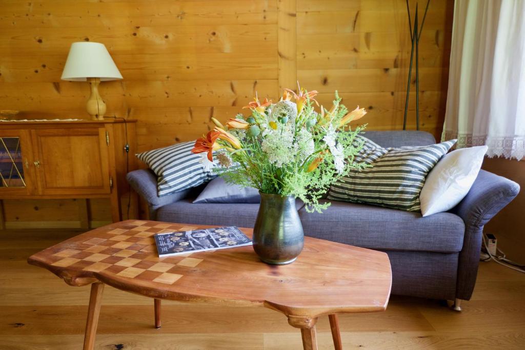 eine Vase mit Blumen auf einem Tisch im Wohnzimmer in der Unterkunft Chalet Ried Naturpark Diemtigtal in Diemtigen