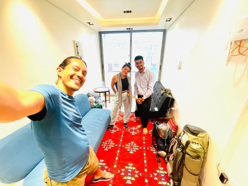 two men and a woman standing in a room with a red carpet at House of Nomads - Hostel in Muscat
