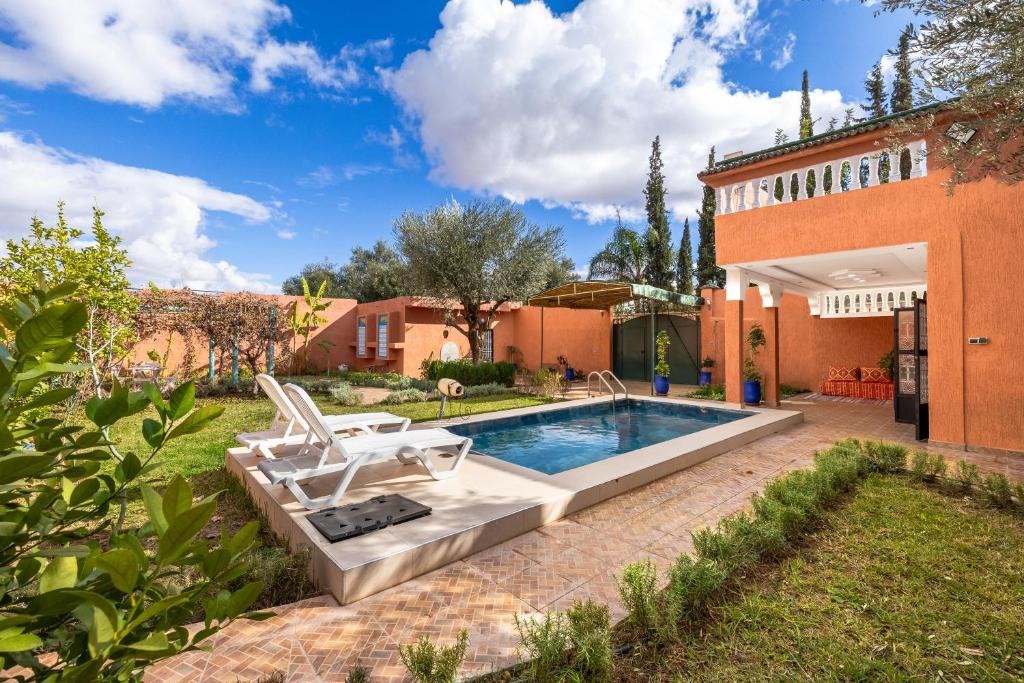 a backyard with a swimming pool with two lawn chairs at Private Villa with Pool and Hammam Marrakech in Oulad Akkou