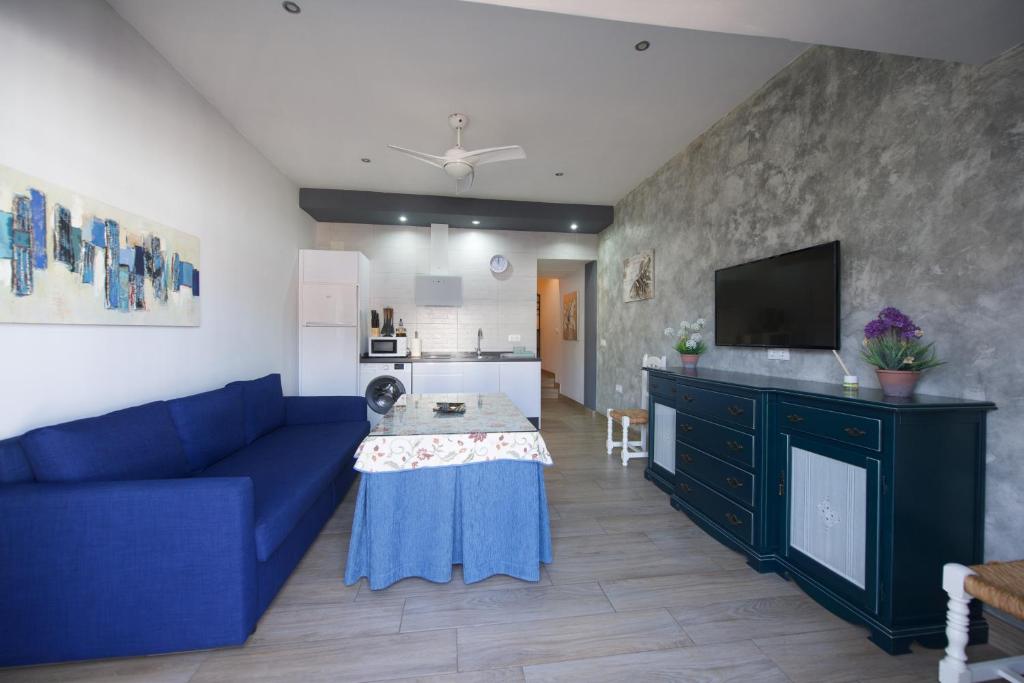 a living room with a blue couch and a kitchen at Apartamentos Turisticos Ilusiones 2 in Cazalla de la Sierra