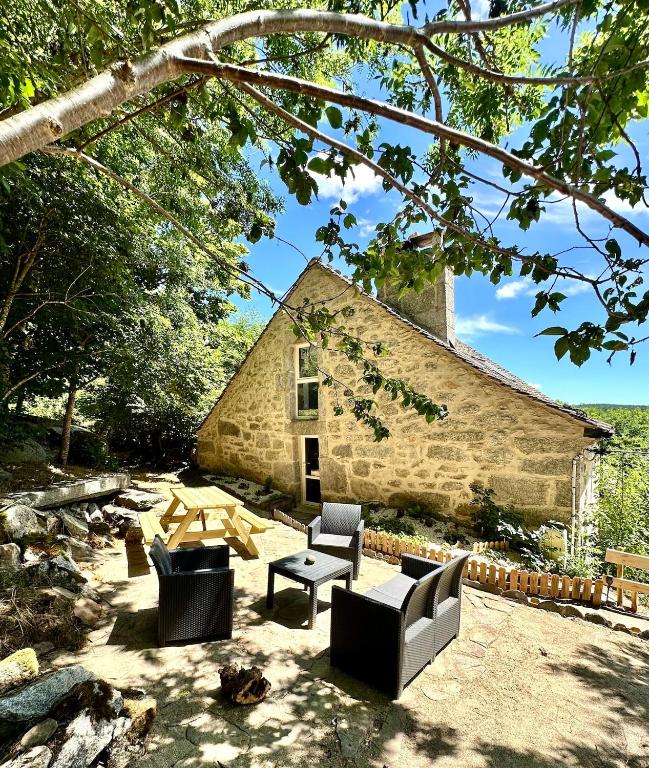 a stone building with chairs and tables in front of it at La Pastourelle en Lozère in Le Bacon
