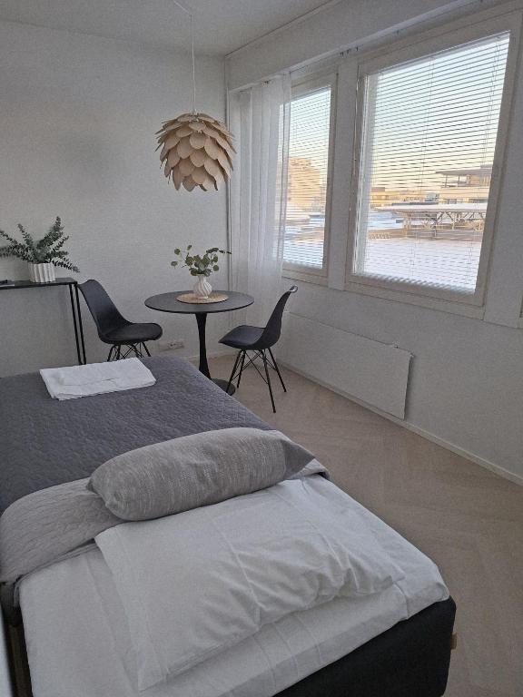 a bedroom with a bed and a table and windows at Centrum Apartment Kokkola in Kokkola