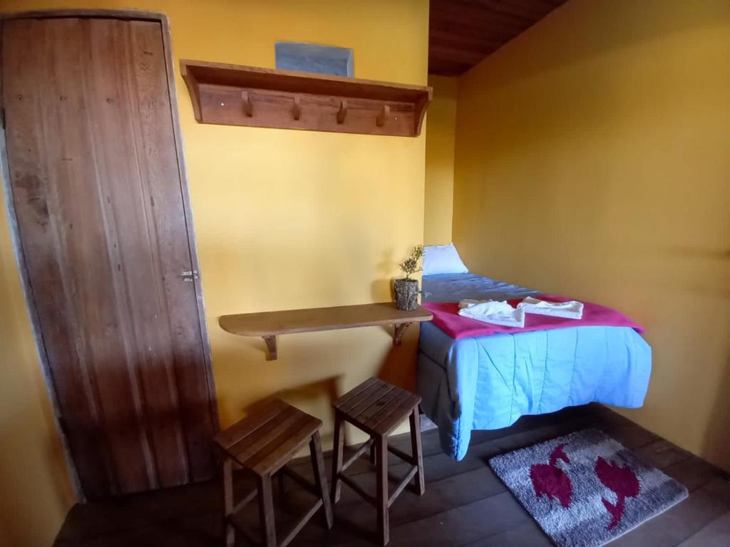 a small room with a bed and a table and chairs at Bituca Hostel e Café in Milho Verde