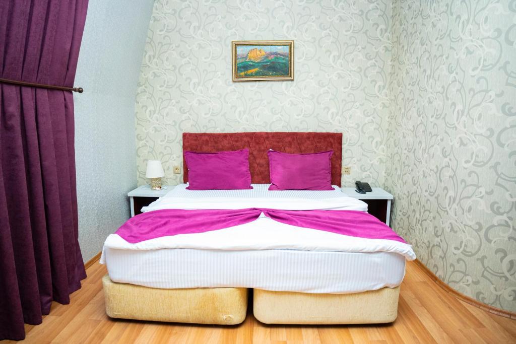 a bedroom with a large bed with purple pillows at Nemi Boutique Hotel in Baku
