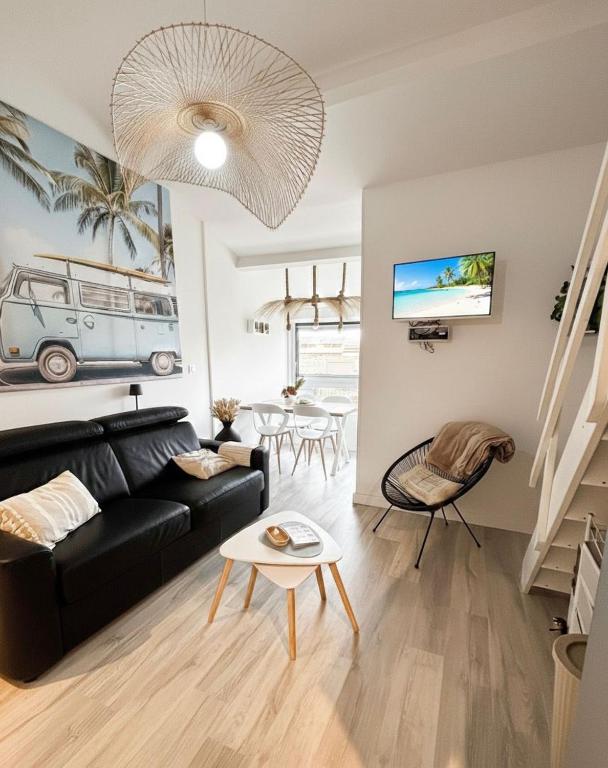 a living room with a black couch and a table at Le Van T2 Spacieux 44m2 wifi Clim in Valras-Plage