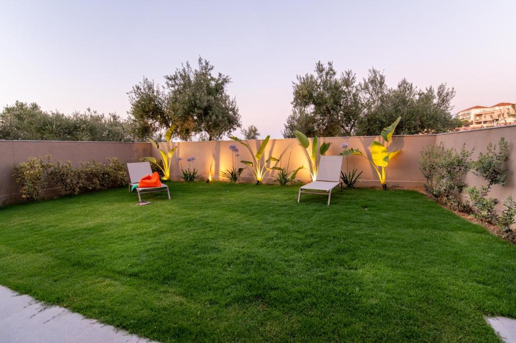 a yard with two chairs and a fence at Mystrali 2BD Modern Apt with Private Garden in Galatás