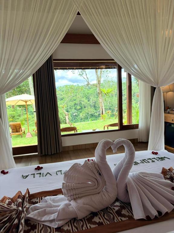 two swans making a heart shape on a bed at Wana Ayu Jelijih Villas by Dhananjaya Hospitality in Tampaksiring