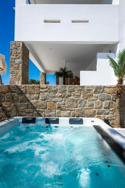 a swimming pool in a house with a stone wall at Double M Adults Only in Ano Mera