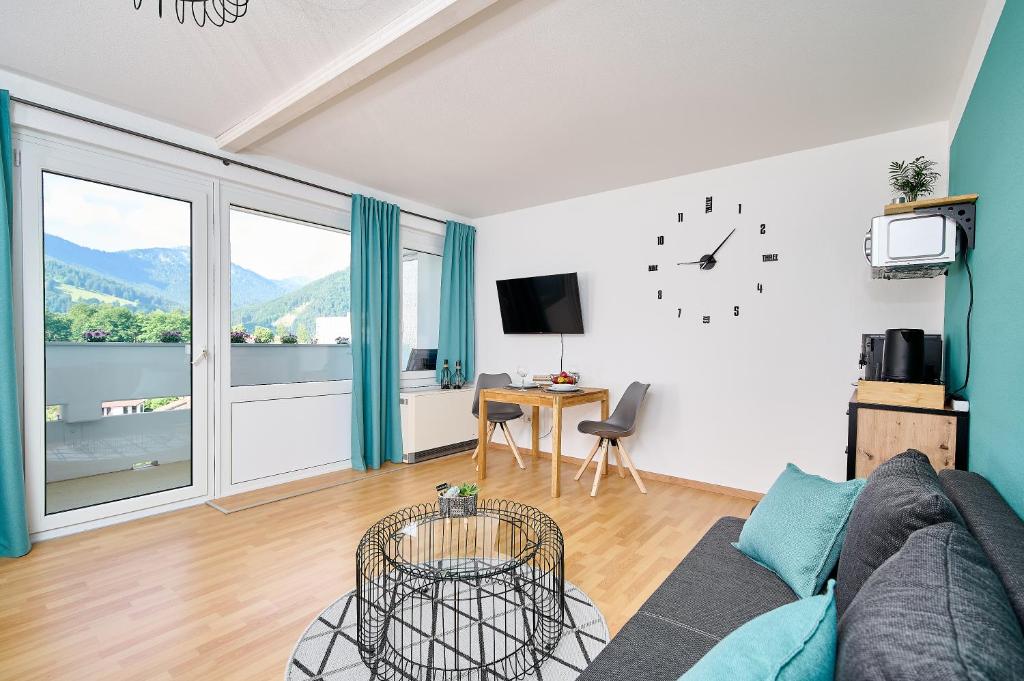 a living room with a couch and a clock on the wall at Asmus Unterkunft in Immenstadt im Allgäu