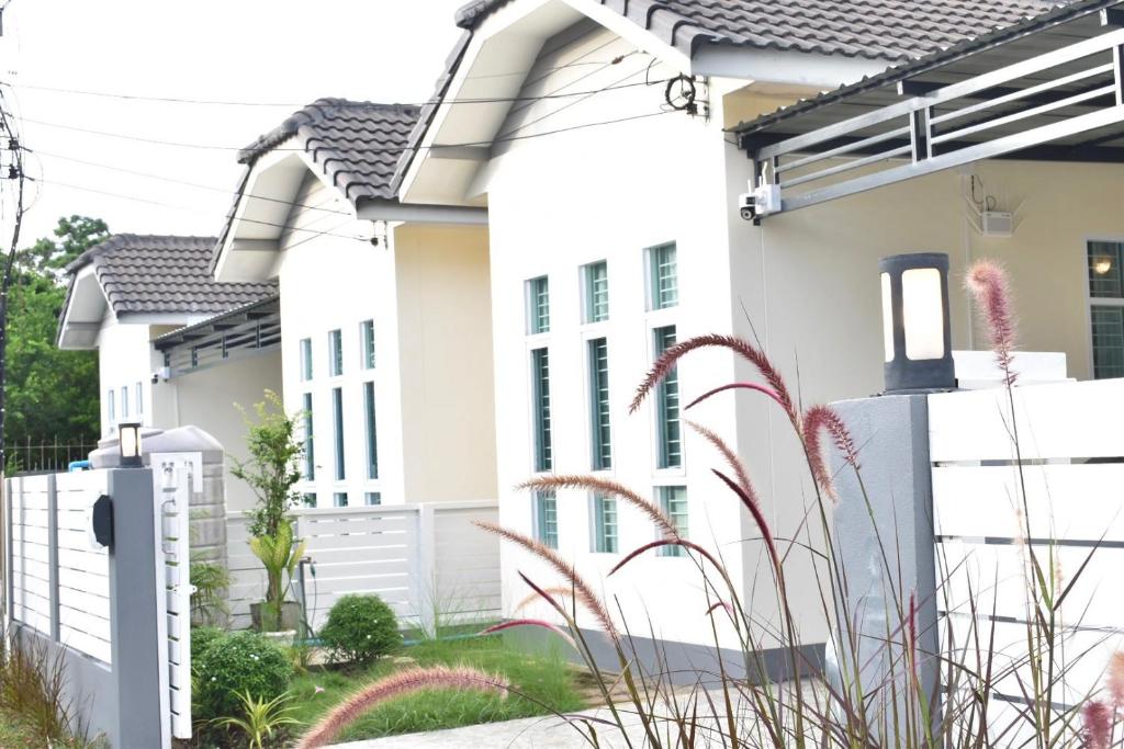 a white house with a white fence at Khwanlom House in Lampang