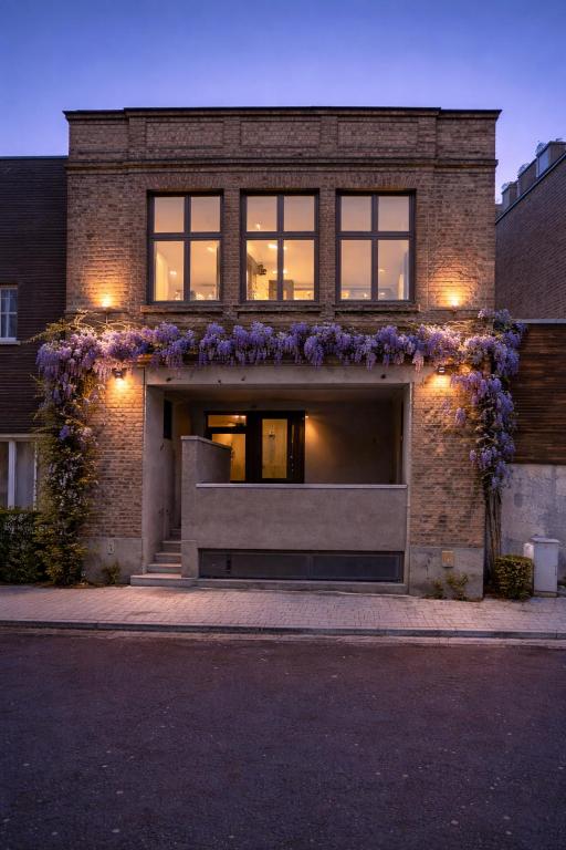 a brick building with purple flowers on it at Burgschelde 63 in Oudenaarde