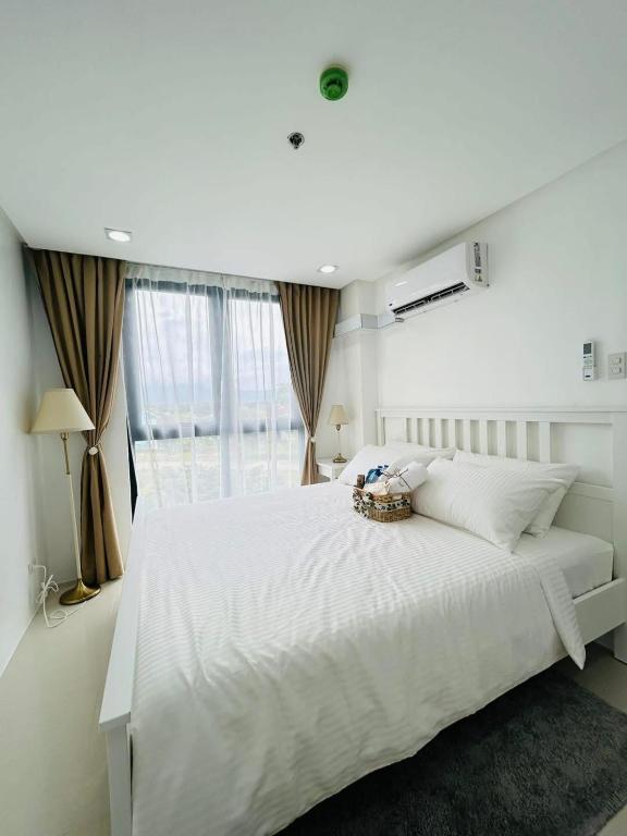 a white bedroom with a large bed and a window at Unit 509 - One Pontefino Tower in Batangas City