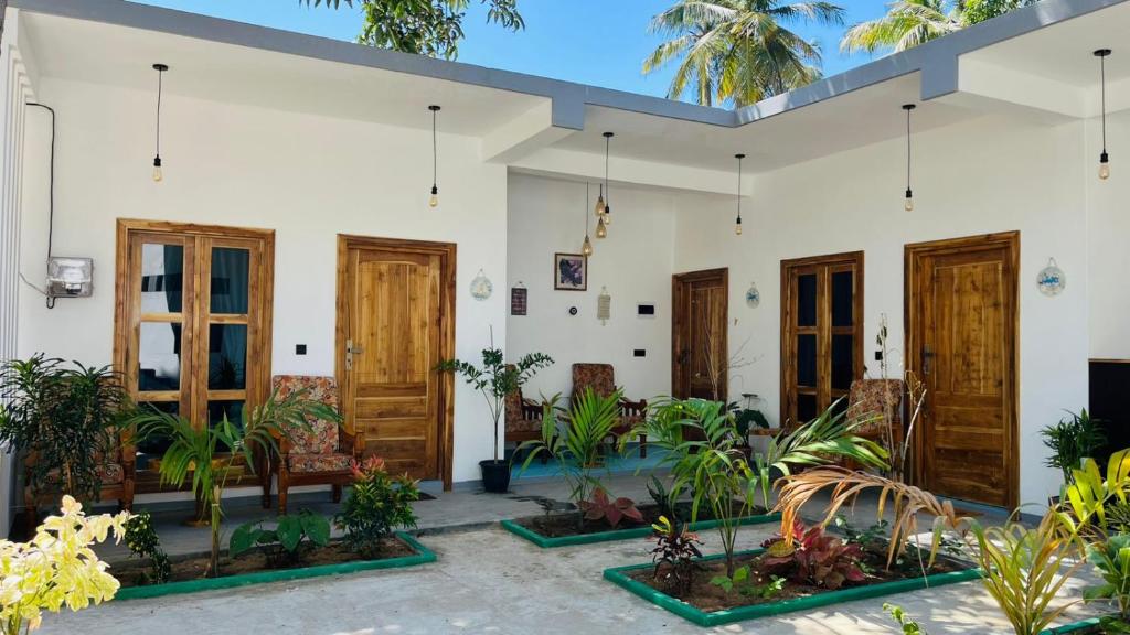 a white building with wooden doors and plants at Breezy Resort in Arugam Bay