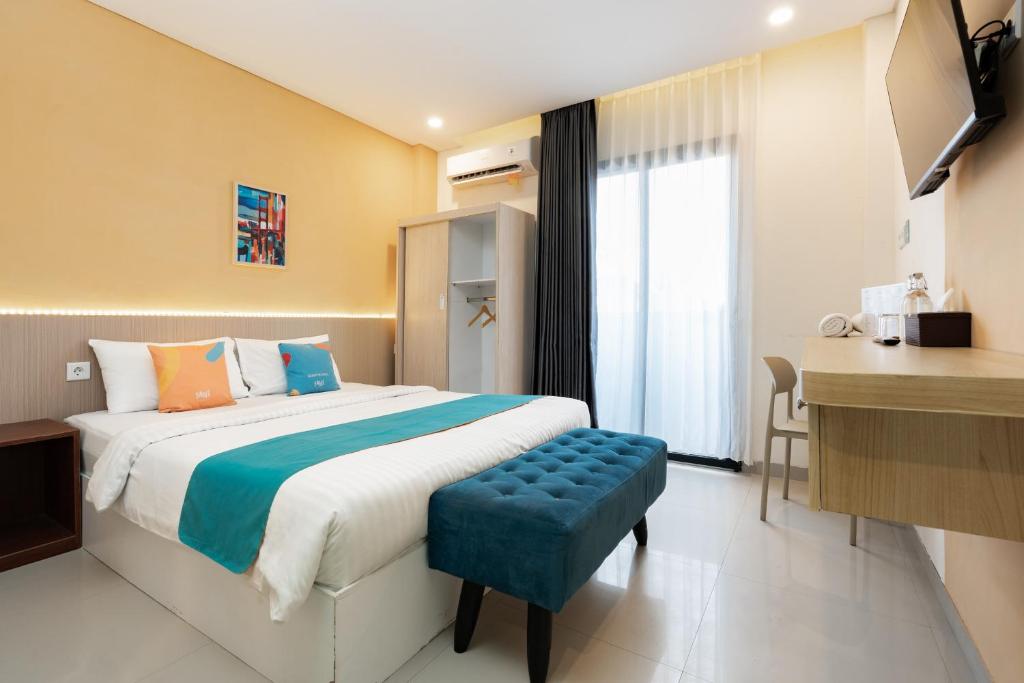 a hotel room with a bed and a desk at Sans Hotel Elrose Place in Samarinda