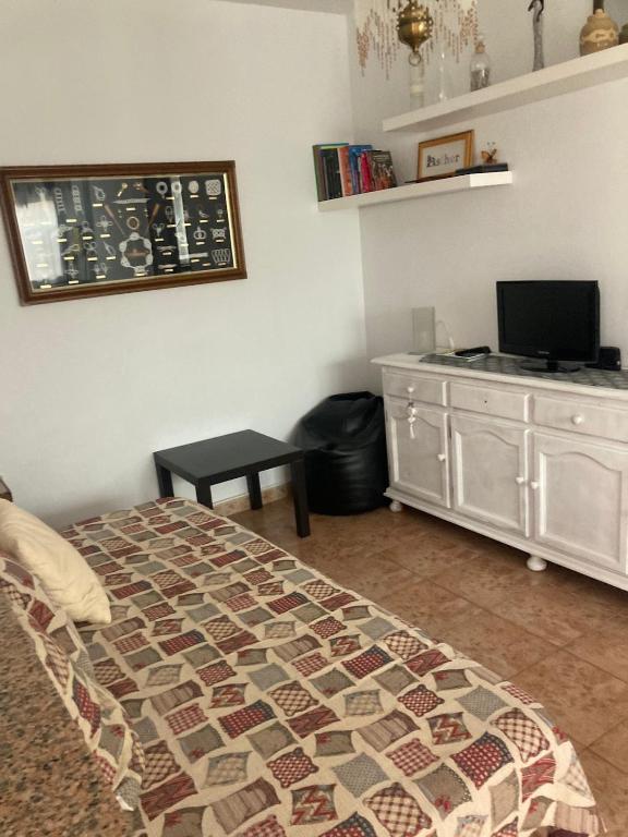 a bedroom with a bed and a dresser and a television at Liencres Apartment in Liencres