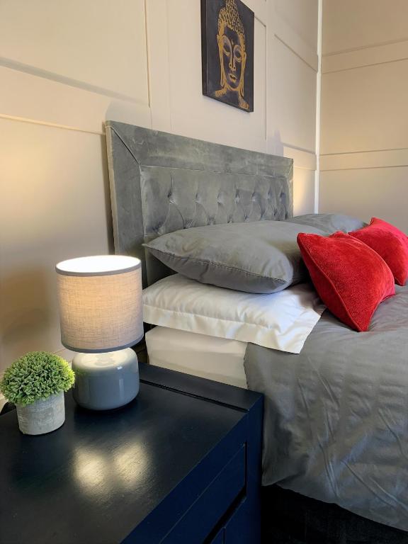 a bedroom with a bed with red pillows on it at Springfield Apartment - Train to Glasgow or Edinburgh - Private Parking & Wifi in Airdrie
