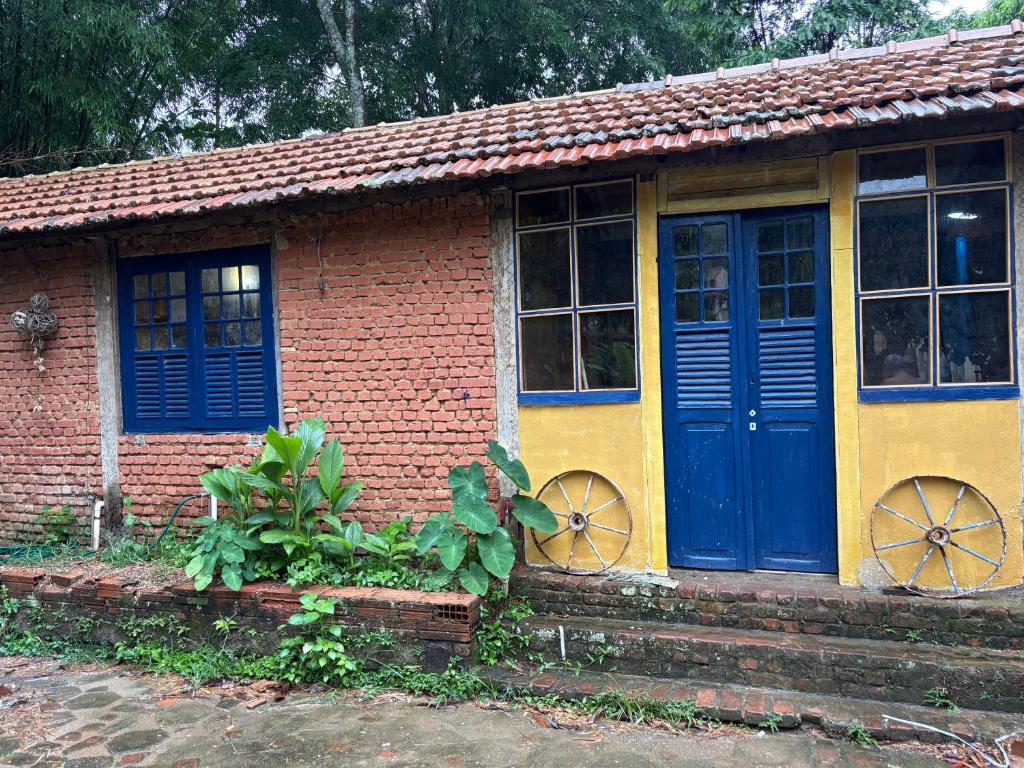 a small brick house with blue doors and windows at Casinha Rústica de Paty in Paty do Alferes