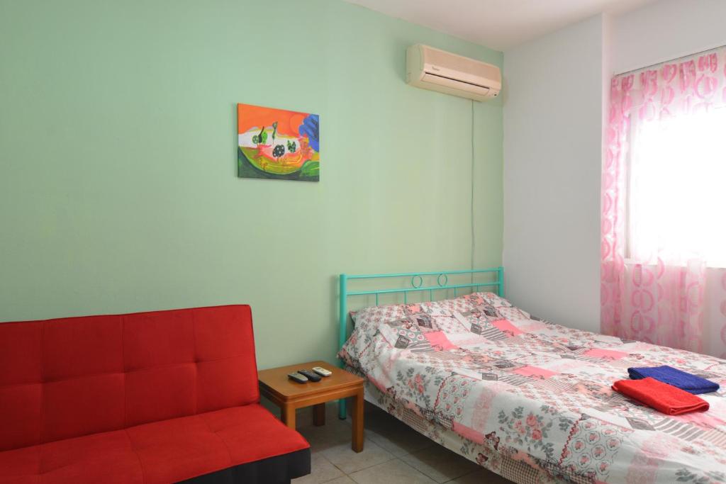 ハニア・タウンにあるEconomy Studio Apartmentsのベッドルーム1室(ベッド1台、赤い椅子付)
