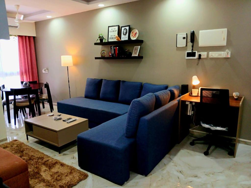 a living room with a blue couch and a table at Lakefront Lounge-Luxe 1bhk condo with 2queen beds-2baths in Mumbai
