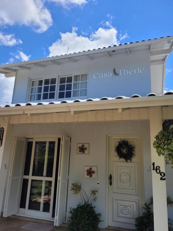 a white house with a sign on top of it at Pousada Casa Thede in São Salvador