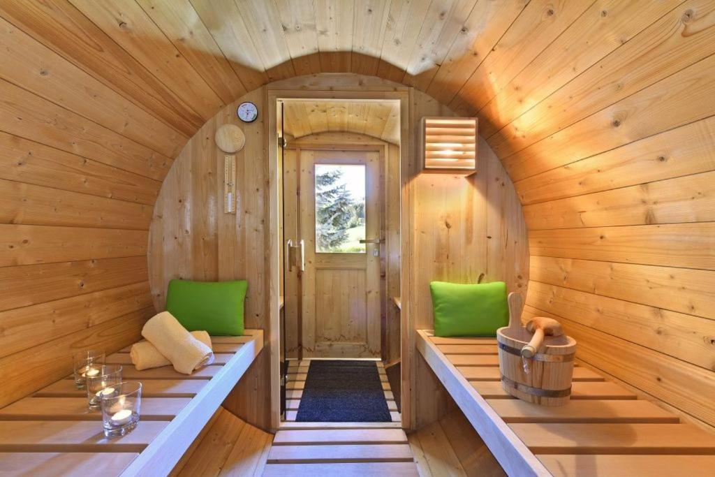 a wooden room with green chairs and a door at Superior Apartments Giovannini in Fai della Paganella