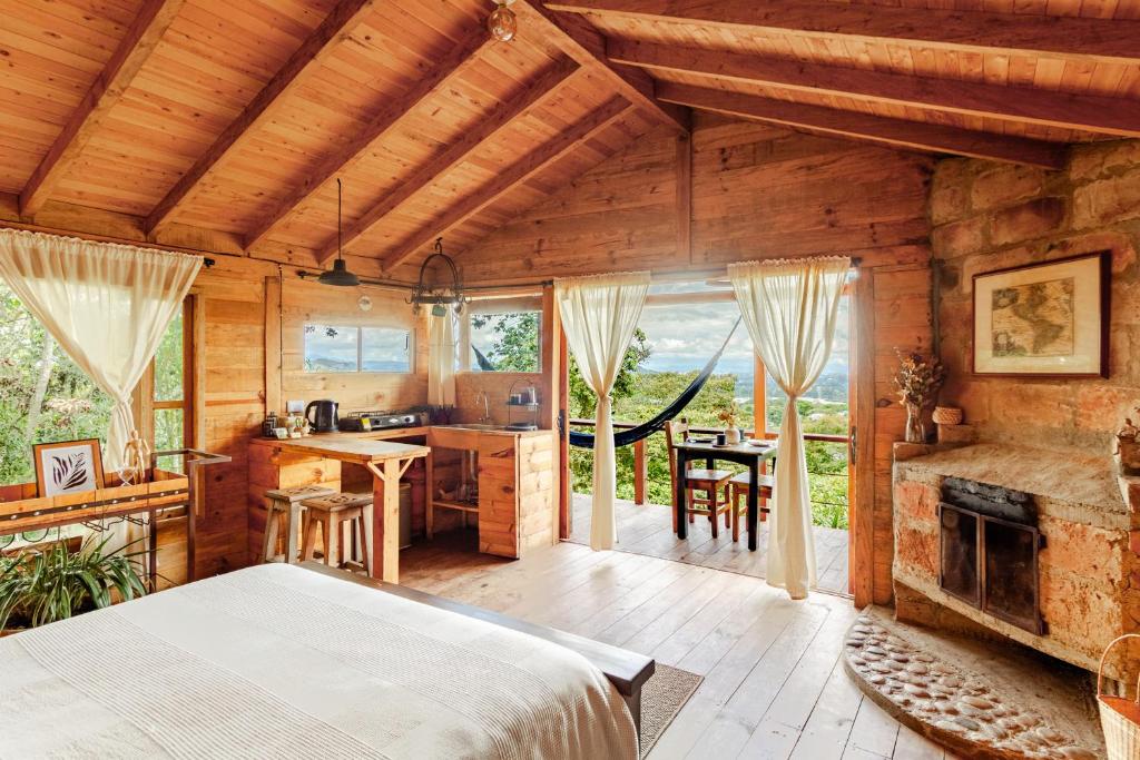 a bedroom with a bed and a kitchen with a fireplace at Refugio para desconectar, cabaña del ermitaño en medio del bosque in La Ceja
