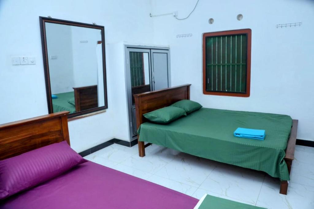 a bedroom with two beds and a mirror at Jaffna Bungalow in Jaffna