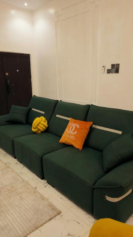 a green couch with an orange pillow on it at Fukusu II in Ikuata