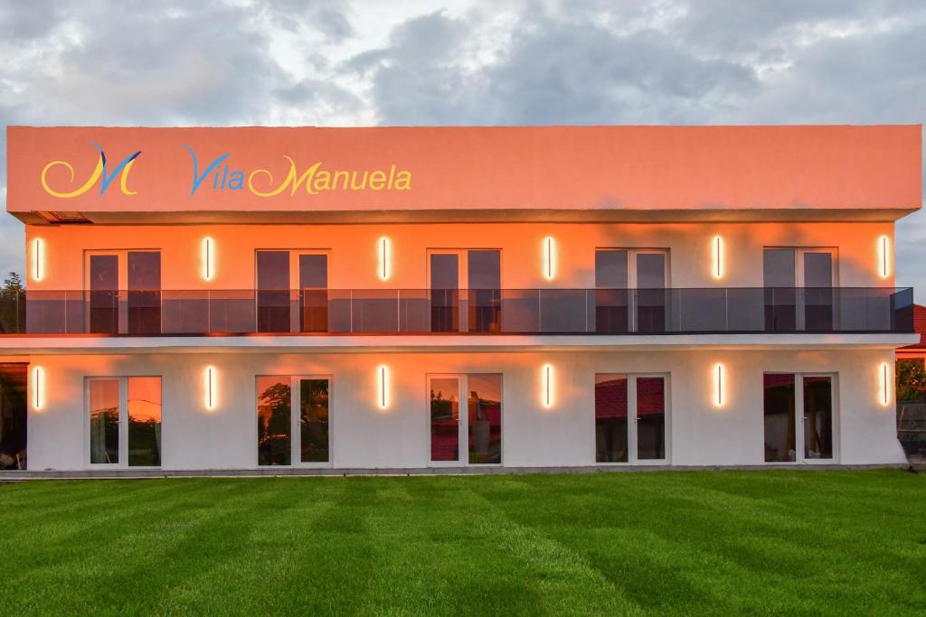 an orange and white building with a green lawn at Vila Manuela Techirghiol in Techirghiol