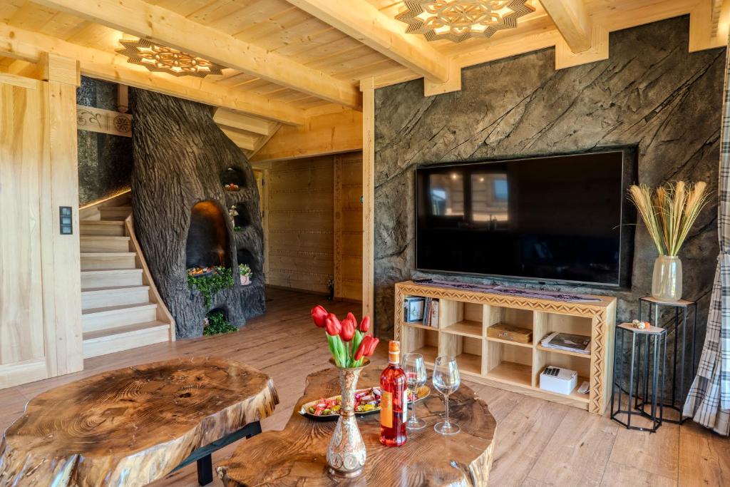 a living room with a table and a large tv at Domki Góralska Przystań in Białka Tatrzańska